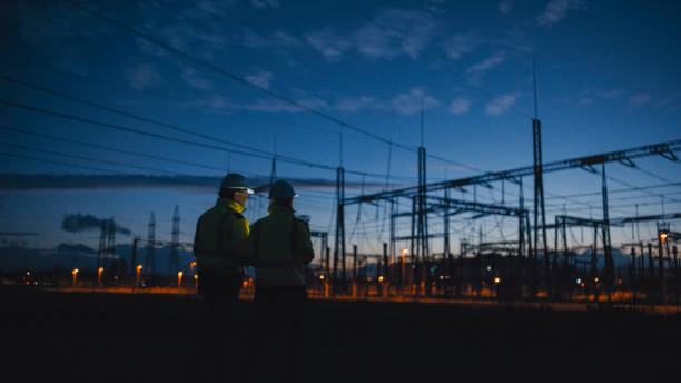 istock Rear View Of Determined Electrical Engineers Looking At Silhouette Transformers At Night 1777966591