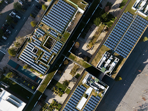 Overhead aerial rising view of a residential area and apartment block with solar panels installed on the rooftops