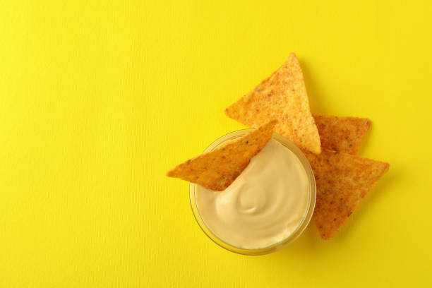 istock Bowl with cheese sauce and chips on yellow background 1777976114