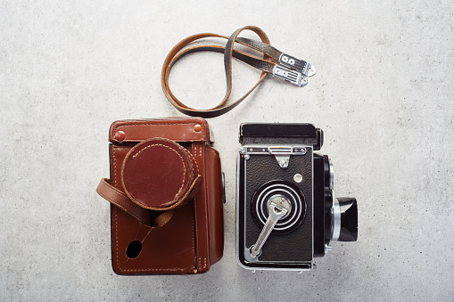 Vintage twin lens reflex (TLR) medium format camera with leather case on concrete table background