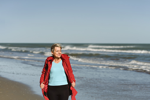Senior woman walking on a stormy beach.