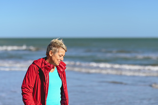Portrait of a short haired mature woman walking on a winter beach.