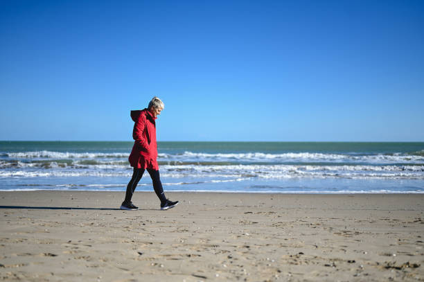 istock Senior woman walking through sand dunes in an empty beach. 1777985046