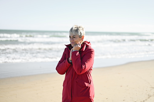 Portrait of a mature woman with short hair enjoying the retirement in an autumn beach.