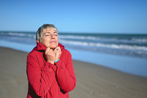 Mature woman with eyes closed relaxing on a beach.