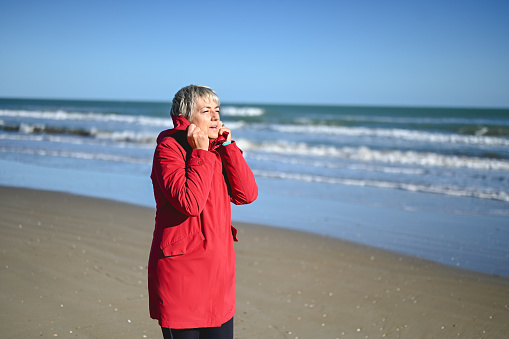 portrait of mature woman in a red raincoat on a winter beach.