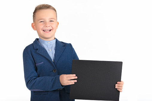 Happy exited caucasian young boy showing and displaying blank black board ready for your text or product.White background isolated.
