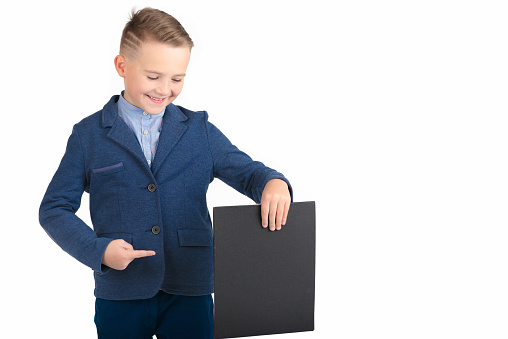 Happy exited caucasian young boy showing and displaying blank black board ready for your text or product.White background isolated.