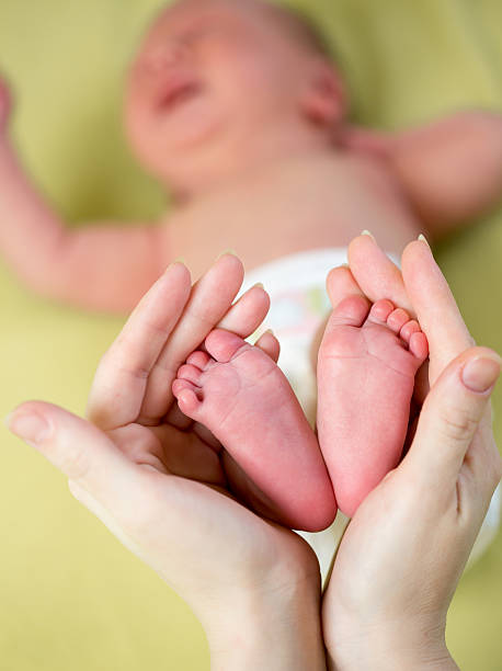 istock mother hands holding small baby's feet 177799373