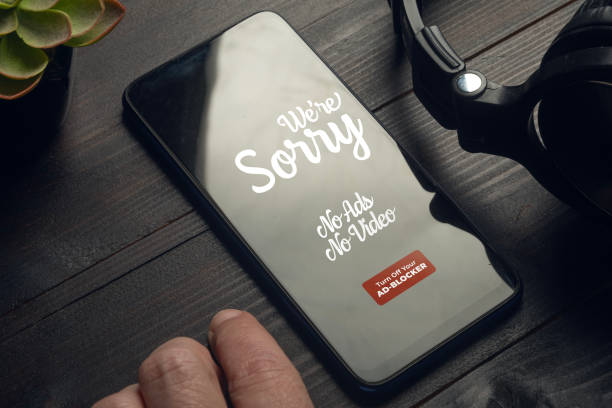 istock Ad blocker concept: smartphone on a wooden table with a headphone set 1777994703