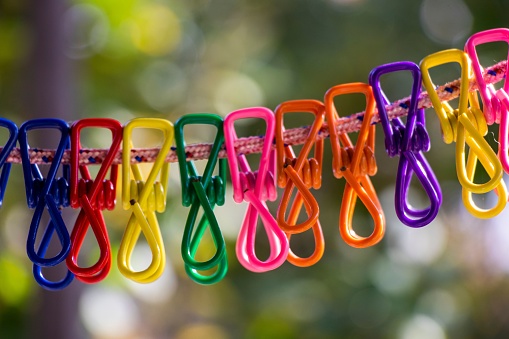 A closeup shot of colorful plastic clothespins hanging from a clothesline