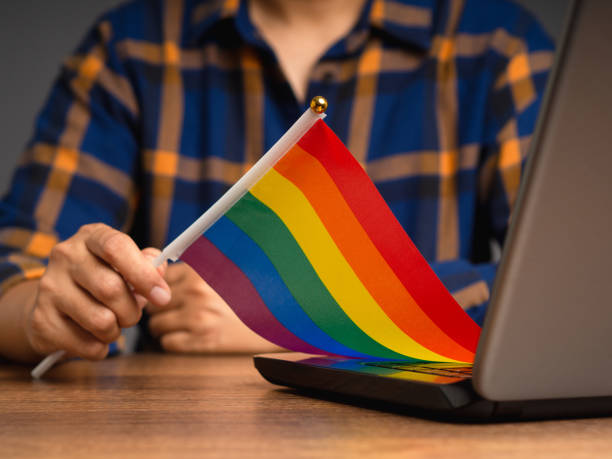 istock Rainbow flag showing in hand while sitting at the table in the office 1778002083