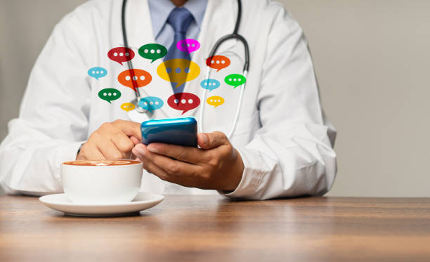 istock Doctor in a uniform using a smartphone with colorful chat icons on application digital web and social media while sitting at the table 1778005983