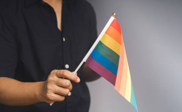 istock Rainbow flag showing in hand while standing against a gray background 1778006543