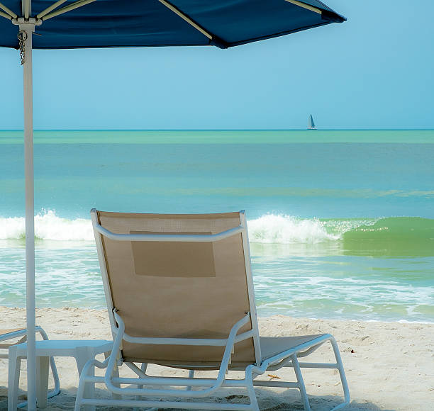Beach Chair Under an Umbrella for Relaxation, Naples Florida USA Beach Chair Under an Umbrella for Relaxation, Naples Florida Beach USA naples beach stock pictures, royalty-free photos & images