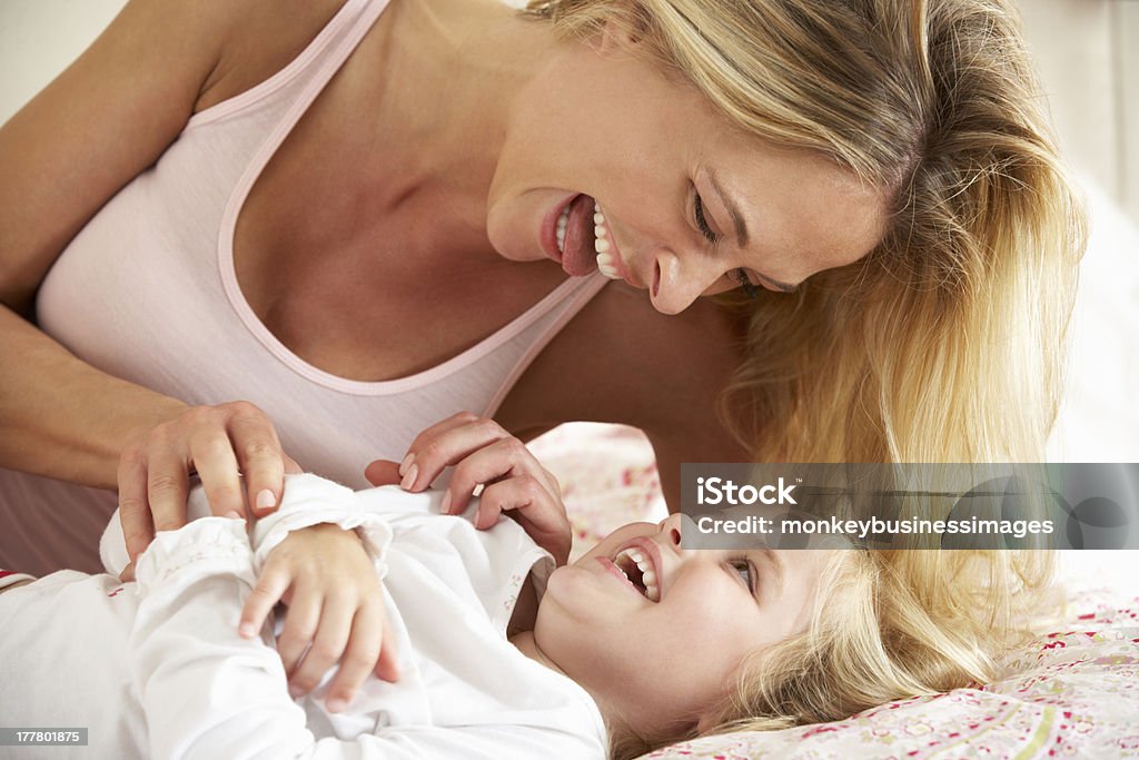 Mother And Daughter Relaxing Together In Bed Mother And Daughter Relaxing Together In Bed Playing Around Laughing Tickling Stock Photo