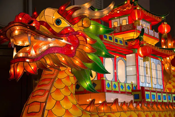 Giant dragon boat shaped multicolored Asian lanterns glowing.