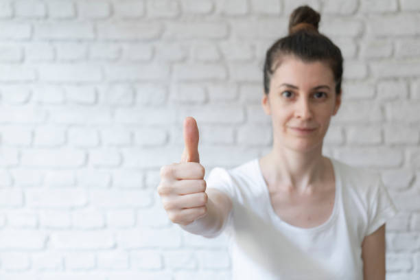 Young woman is holding thumbs up over