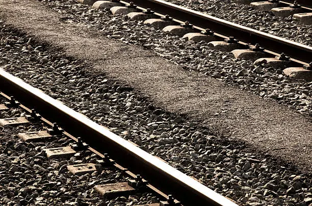 Railways sleepers and stones with bright of the Sun on the rails perspective.