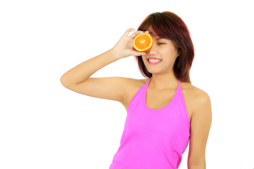Isolated young asian woman with pieces of orange