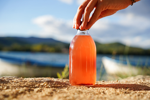 Probiotic and refreshment lemon drink. Homemade fermented kombucha tea in a glass bottle with a lake of background