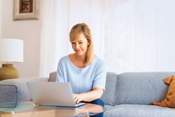 istock Blond haired woman sitting at home and using laptop for work 1778036876