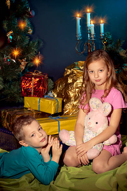 Little boy and girl near Christmas tree.Gifts stock photo