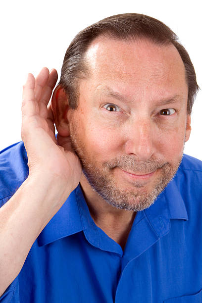 Senior Hard Of Hearing Senior man with a hearing loss cups his hand to his ear to help hear the sounds. old man cupping his ear to hear something stock pictures, royalty-free photos & images