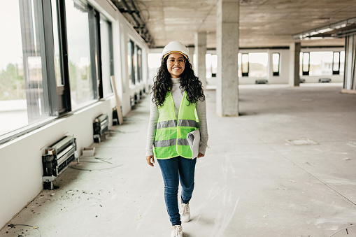 Young female Indian engineer on the construction site - inspecting