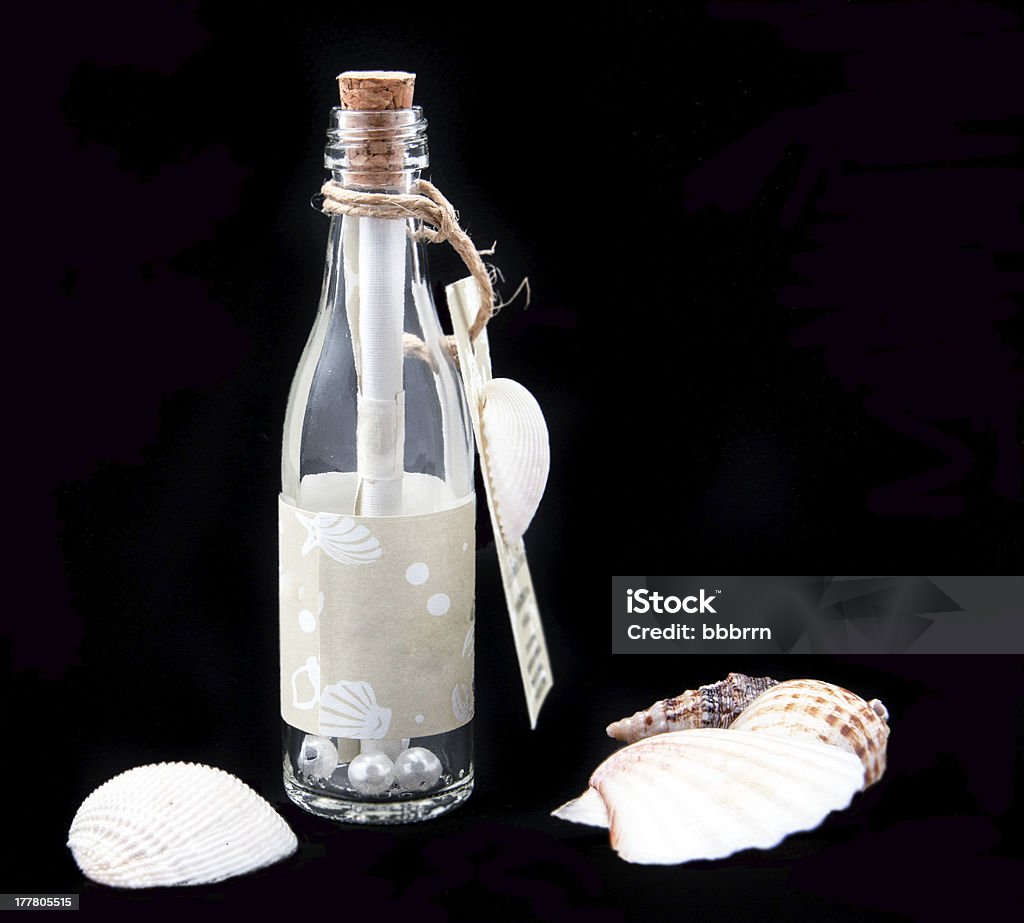 message in a bottle seashells and message in a bottle on black Animal Shell Stock Photo