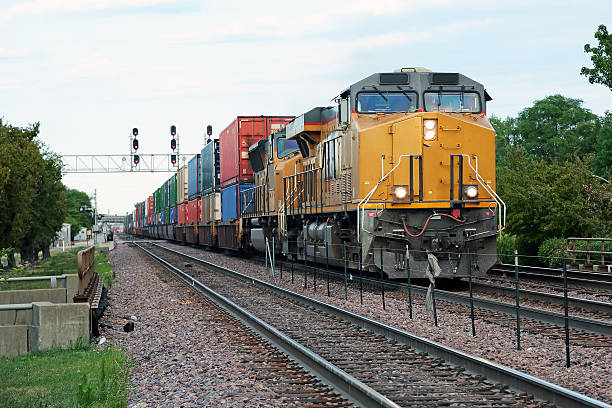 Two yellow locomotives and double stack freight train Two yellow locomotives and double stack freight train passing through town freight train stock pictures, royalty-free photos & images
