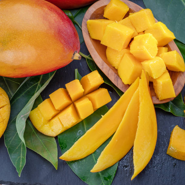 istock Ripe mango fruits with slices and mango leaves on a gray stone table. Nice fruit background for your projects. 1778058080