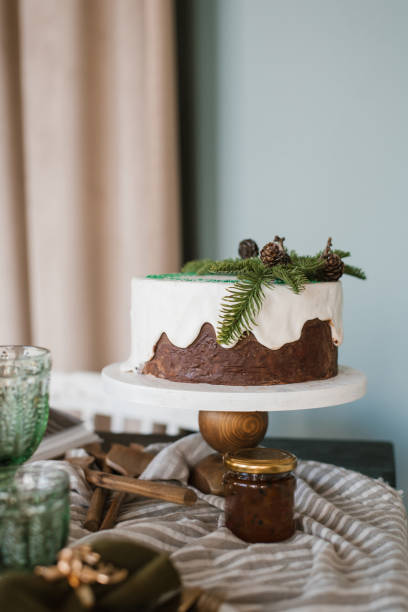Festive Christmas cake with white icing decorated with spruce branches stands on a set table