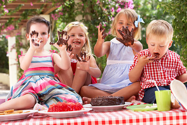 grupo de niños comiendo torta en tea party al aire libre - tea party party tea little girls fotografías e imágenes de stock