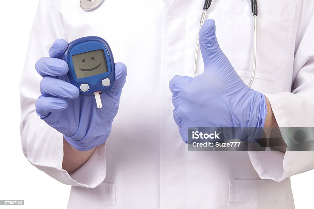 Doctor holding blood sugar meter. Showing OK sign Doctor holding blood sugar meter and showing OK sign. Isolated on white Concepts Stock Photo