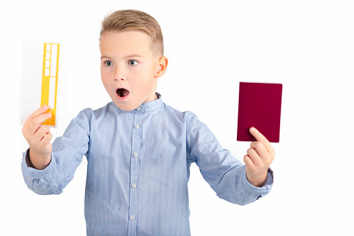 European smiling,surprised boy in blue shirt hold ticket and passport. isolated on white background.Close up.