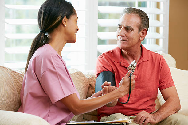 el personal de enfermería visita senior paciente de sexo masculino en su hogar - blood pressure gauge surveillance home interior house fotografías e imágenes de stock