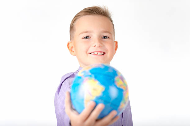 istock Close up Playful young caucasian school boy holding and shows in front a globe on white studio background. 1778075608