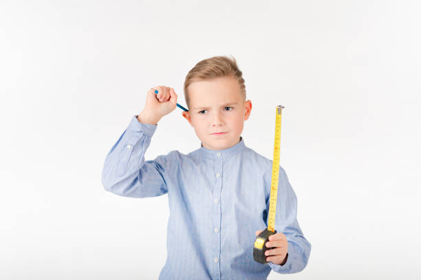 Little boy stretches roulette and pencil something is thinking. Childhood education development Isolated on white background.