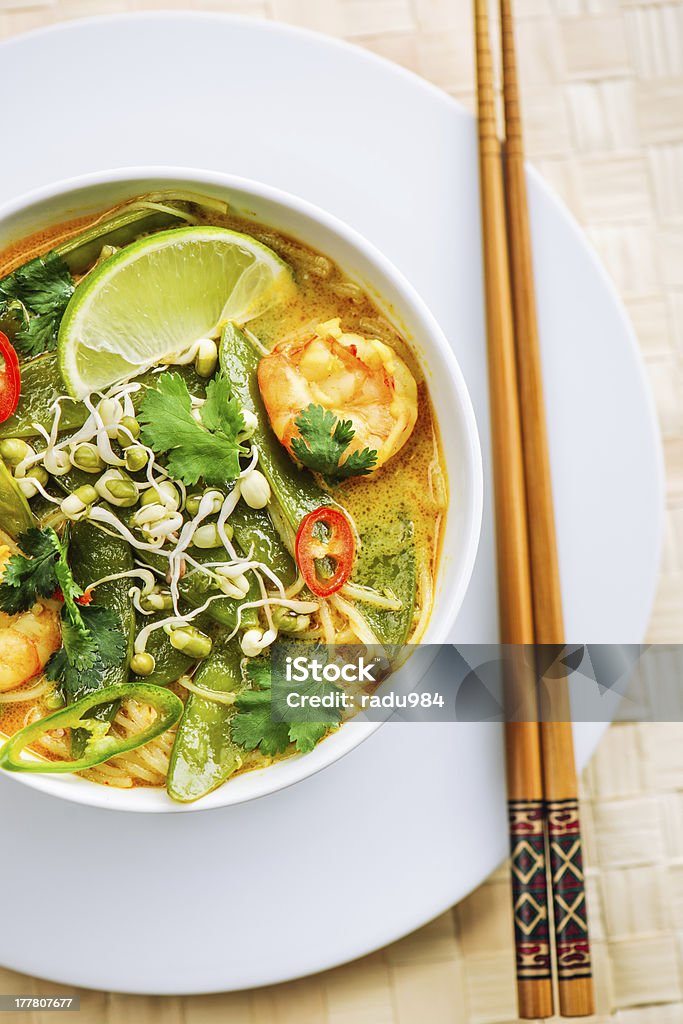 Prawn Laksa Top view of a bowl with prawn laksa. This thai dish is a fresh curry soup with prawns, chili, bean sprouts, noodles, lime and herbs and it is on a simple restaurant setting. Asian Culture Stock Photo