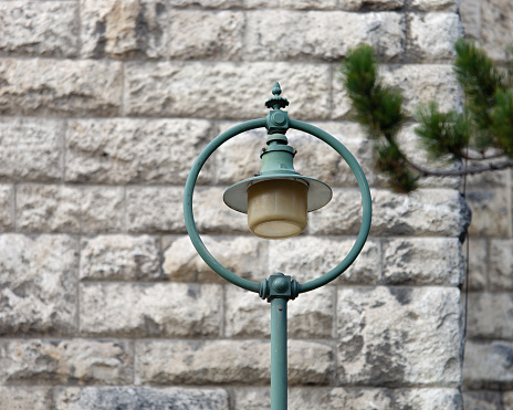 Close-up photo of a vintage green lamp placed in front of the wall of the Church of Saint Anthony of Padua, Zagreb, Croatia