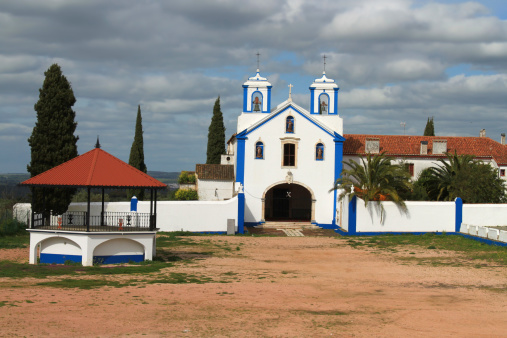 Whitewashed catholic church with blue trimming in Vila Vicosa, Altantejo, Portugal under cloudy sky