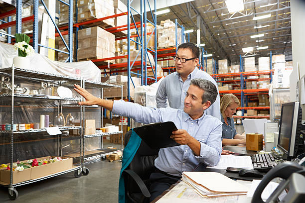 2 businessmen staring at some warehouse racking Business Colleagues Working At Desk In Warehouse Holding Clipboard warehouse office stock pictures, royalty-free photos & images