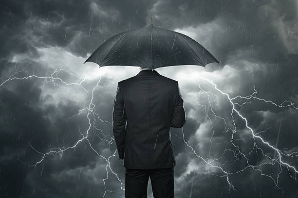 Trouble ahead concept Businessman with umbrella standing in the rain recession protection stock pictures, royalty-free photos & images