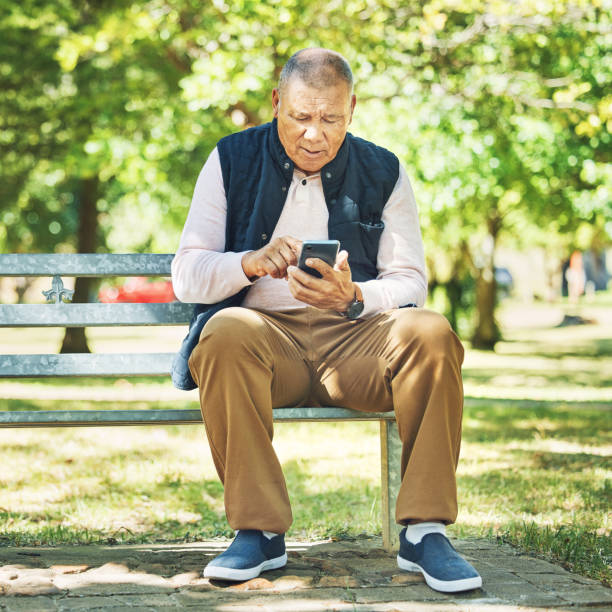 istock Senior man, typing and phone on park bench, learning and network with technology online, nature and outdoor. Elderly person, message and email on smartphone, digital and contact in retirement 1778101294