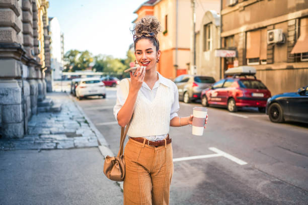 woman sending a voice message while walking outdoors - vocoder imagens e fotografias de stock