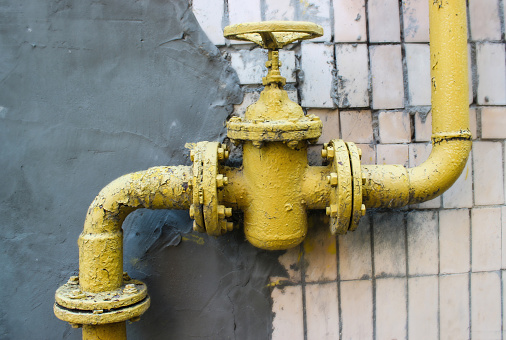 background of an old gas faucet on the background of the remnants of the tile and the bitumen surface