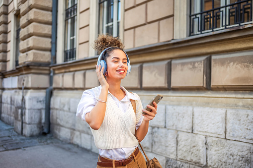 Happy smiling woman enjoying while listening to music in the city