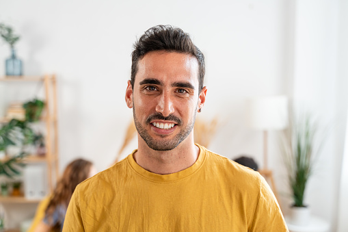 portrait of smiling man in yellow t-shirt at modern home