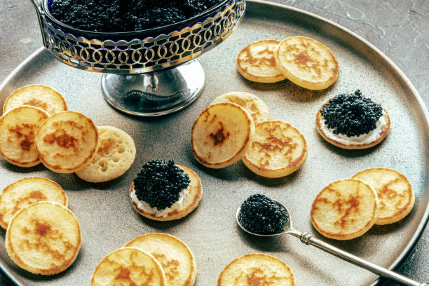 istock Blinis with black caviar and cream cheese, on a festive dish on black 1778128956